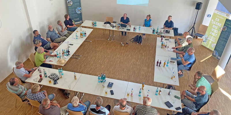 Personen sitzen gemeinsam um einen Tisch und beraten