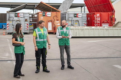 Drei Menschen vor Abfallcontainern