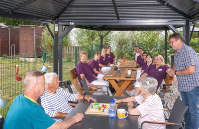 Bewohnerinnen und Bewohner sowie das Personal entspannen unter Pavillons
