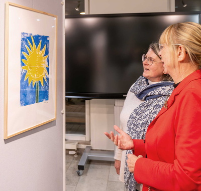 Zwei Frauen betrachten einen bunten Linoldruck