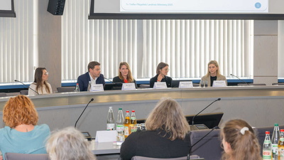 Blick aus dem Publikum auf das besetzte Rednerpult im Sitzungssaal