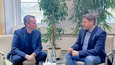 2 Personen sitzen gemeinsam an einem Tisch und reden miteinander