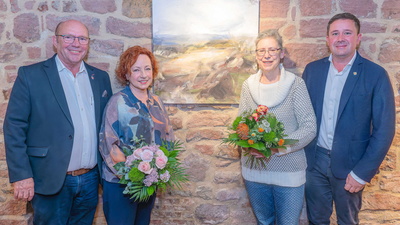 Vier Personen vor einem Bild an der Wand