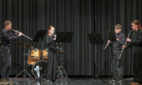 Vier Jugendliche spielen mit Blasinstrumenten