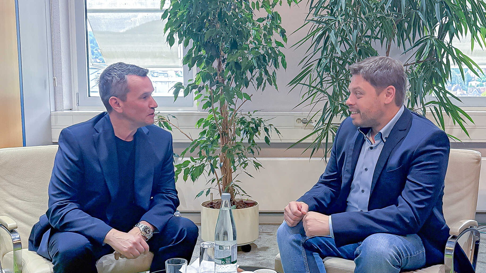 2 Personen sitzen gemeinsam an einem Tisch und reden miteinander