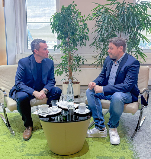 2 Personen sitzen gemeinsam an einem Tisch und reden miteinander