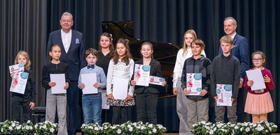 Kinder mit Urkunden vor Klavier