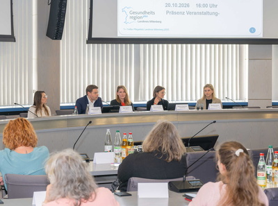 Blick aus dem Publikum auf das besetzte Rednerpult im Sitzungssaal