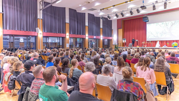 Gäste verfolgen den Vortrag auf der Bühne