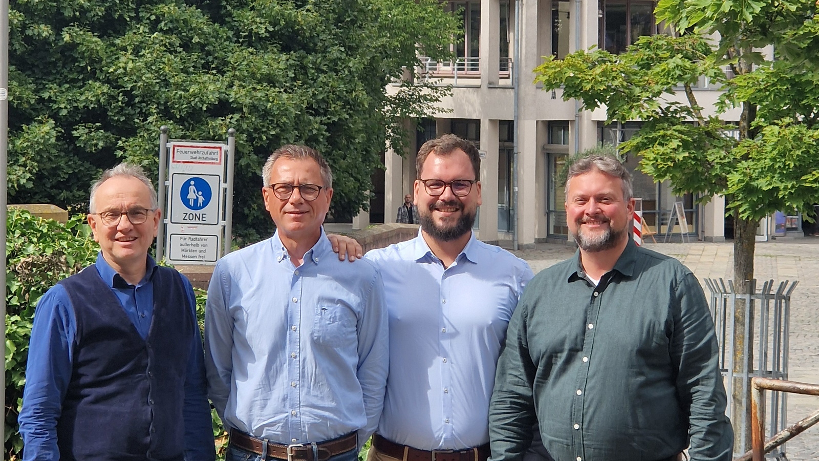 Vier Personen im Hintergrund ein Haus mit Solaranlage