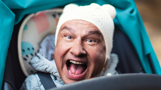 Das schreiende Gesicht eines Erwachsenen im Körper eines Babys im Kinderwagen