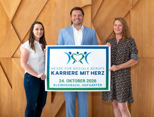 Drei Menschen halten ein Plakat zur Veranstaltung hoch