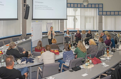 Eine Personengruppe im Sitzungssaal vor einer Pinnwand