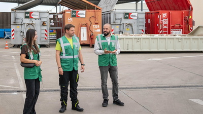 Drei Menschen vor Abfallcontainern