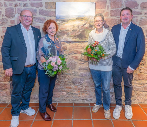 Vier Personen vor einem Bild an der Wand