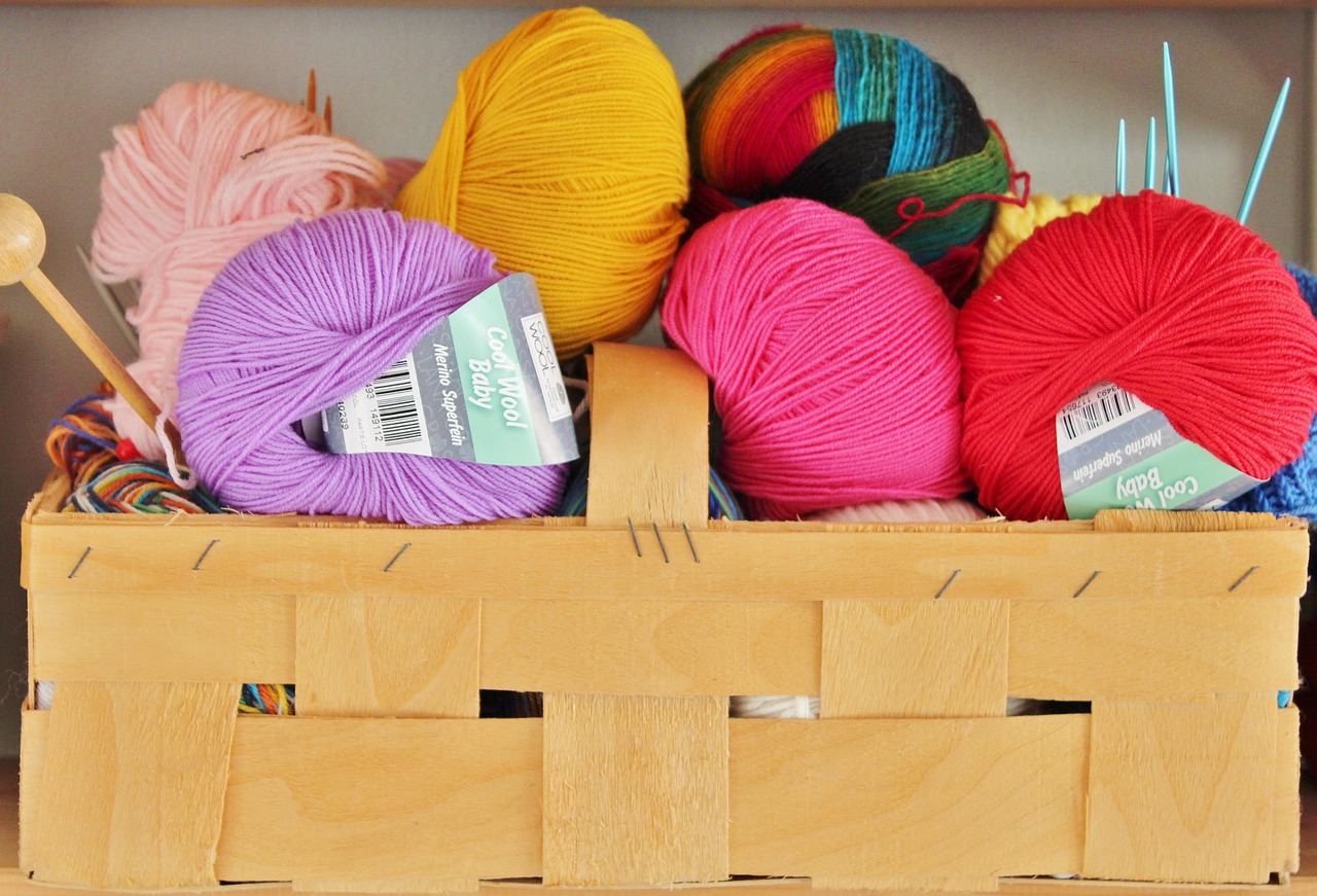 Korb mit bunten Wollknäuelen und Stricknadeln